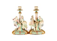 A pair of 19th Century Continental porcelain figural decorated candlesticks, in the form of a
