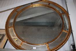 A large circular gilt framed and bevel edged wall