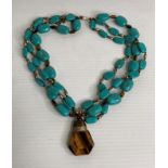 A Kenneth Cole New York turquoise beaded and tigers eye triple strand necklace with signature bar