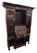 An early 20thC ebonised oak bureau cabinet in the manner of Liberty, the moulded cornice with shaped