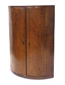 An early 19thC oak and mahogany boxwood and ebony strung bow fronted hanging corner cabinet, 97cm