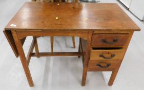 An oak desk, the rectangular top with a drop leaf section, the base with a sliding drawer, above