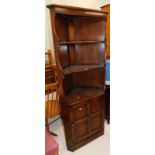 Withdrawn by vendor pre-sale. An Ercol dark elm corner unit, with three shelves, the base with a