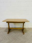 A solid golden oak Ercol style refectory table with shaped trestle ends