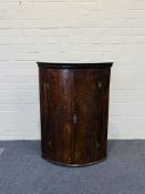 A mid 18th century oak barrel front corner cupboard