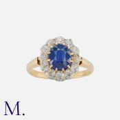 A Sapphire And Diamond Cluster Ring in yellow gold, set with a principal cushion cut sapphire of
