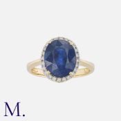 A Sapphire And Diamond Cluster Ring in 14k yellow gold, set with a principal oval cut sapphire of