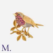 A Ruby Brooch in yellow gold, designed as a robin perched on a branch, pave set with round cut