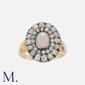 An Opal And Diamond Cluster Ring in yellow gold and silver, set with a central cabochon opal, within