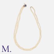A Pearl Necklace in 18 carat yellow gold, comprising two strands of drilled pearls, measuring