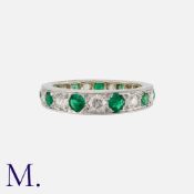 An Emerald and Diamond Band in platinum set with round cut graduating emeralds and diamonds