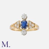 A Sapphire and Diamond Ring in yellow gold, comprising a principal cushion cut sapphire between