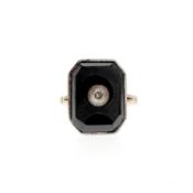 Onyx and diamond ring. The onyx plaque inlaid with a single-cut diamond, inner hoop stamped 9ct,