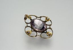 An Edwardian 9ct gold openwork pendant set with central pale oval facet-cut amethyst within a border