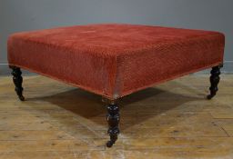 An Edwardian upholstered centre stool, square top upholstered in red fabric, raised on shaped turned