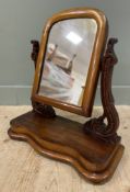 A late19th century mahogany swing mirror, arched top raised on heavily carved scrolling supports, on