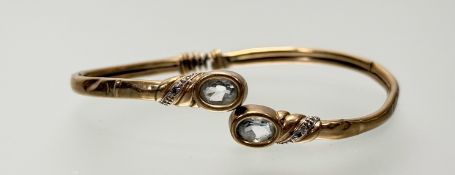 A yellow metal expanding bracelet with oval terminals set facet cut aquamarine and diamond points: