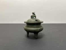 A Chinese bronze incense burner with foo dog to top, raised on three legs with pierced cover (h.
