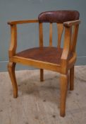 An Edwardian oak desk chair, upholstered back and seat in patinated oxblood leather with brass