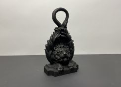 A late 19th/early 20thc cast iron door stop in the form of a lion's head raised on a stepped base (