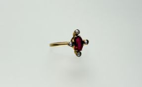 An Edwardian yellow metal ring set oval red faceted stone approximately 0.25ct surrounded by four