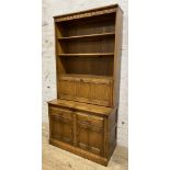 A modern two-part kitchen dresser by Ercol, carved cornice over three open plate racks, over three-