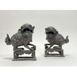 A pair of Chinese cast bronze foo dog temple incense burners with pup, raised on pierced bases (h.