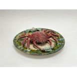 A Majolica Palissay style wall plate, decorated with a large red crab on a green mottled ground,
