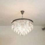 A contemporary metal circular chandelier, with two tiers of bulbs, and four tiers of hanging
