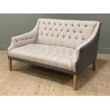 A contemporary Chesterfield-style two seater sofa, with button back and seat upholstered in light