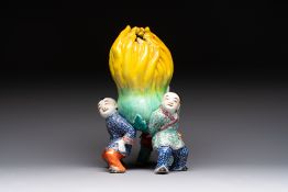 A Chinese famille rose figure of three boys holding a Buddha's hand, Republic