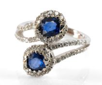 18CT WHITE GOLD TWO-STONE SAPPHIRE & DIAMOND TWIST RING, the two sapphires with border of