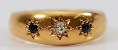 An unmarked 18ct gold sapphire and brilliant cut diamond three stone ring, electronically tested