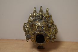 A 20th century gilt metal Tibetan mask incense burner, w12cm.