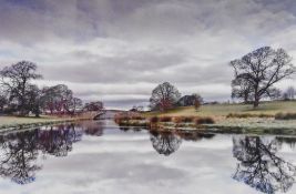 Artist unknown, contemporary photographic print showing a river bridge and trees, within black mount