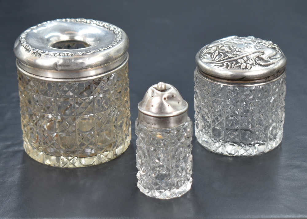A late Edwardian silver capped cut glass cosmetic container, having an embossed floral cap, along - Image 2 of 2