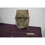 A green canvas frame rucksack containing five leather riding crops