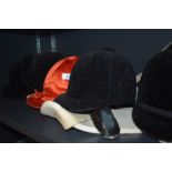 Five riding hats in varying sizes and a back protector one hat marked harry hall