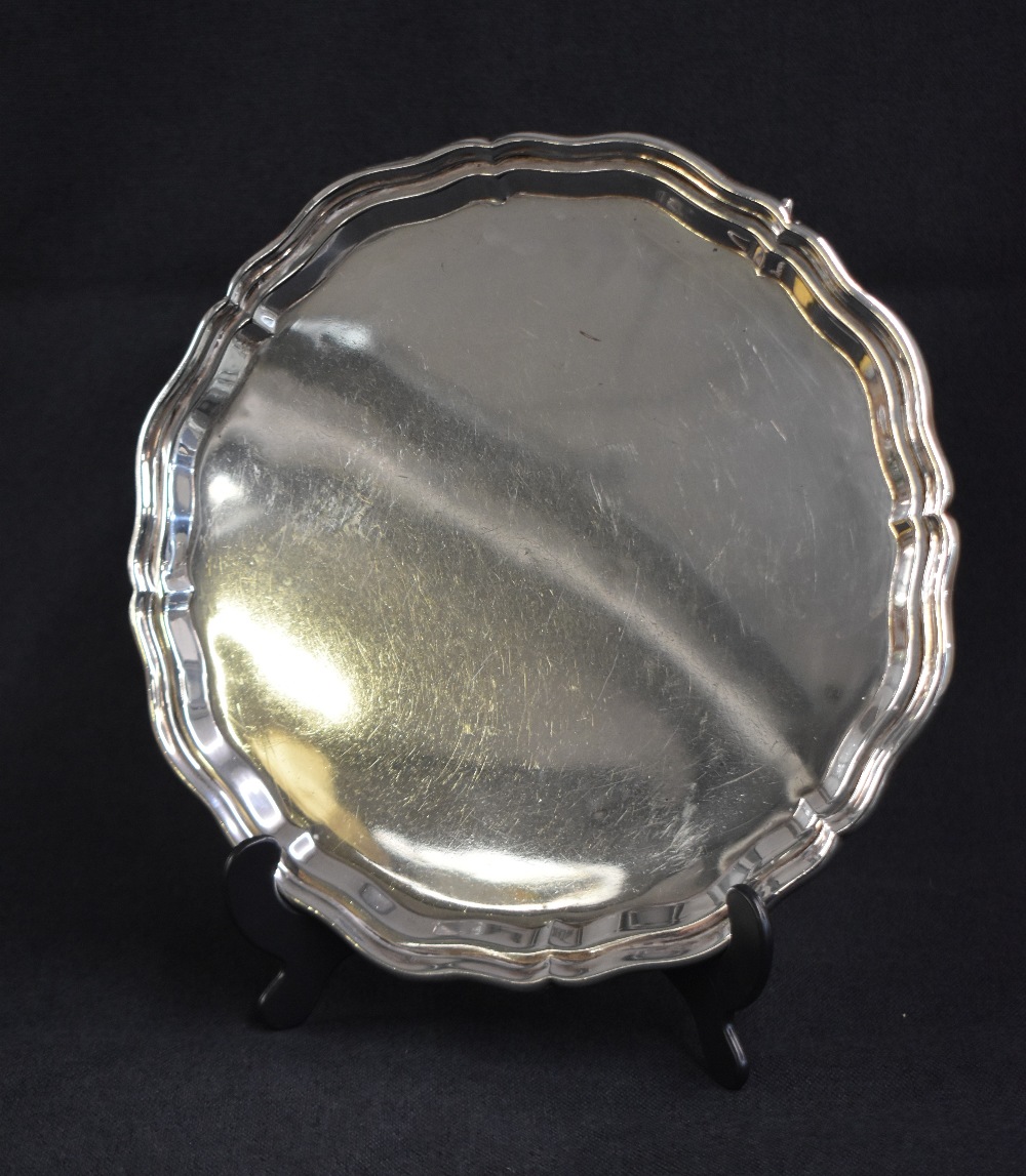 A George V silver salver, of circular form having a Chippendale style rim raised on three scroll