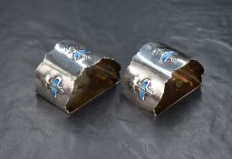 A pair of Edwardian Art Nouveau silver and enamel napkin rings, of crescent form having lobed rims
