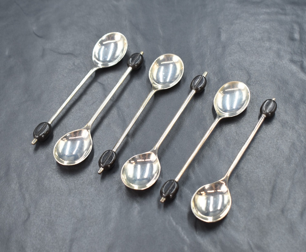 A cased set of six George V silver coffee bean spoons, having black coffee beans to the terminals,