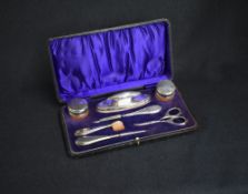 A cased George V silver mounted and capped manicure set, having thread decoration, marks for