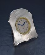 An early 20th century white metal (presumed silver) desk clock, having engine turned decoration to