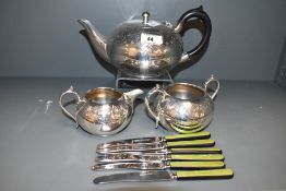 A silver plated coffee pot having black handle and decorated with engraved floral patterns, h10cm,