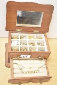 A wooden jewellery box, containing a small assortment of costume jewellery, including hoop earrings,