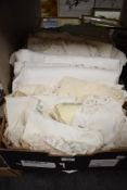 A box containing a selection of assorted linen tablecloths and doilies etc.