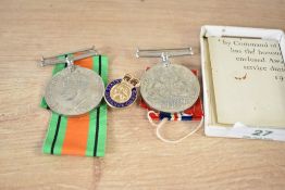 A WWII Defence medal having a narrow central red stripe with a narrow white stripe on either side,