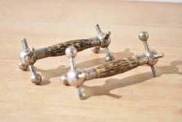 A pair of white metal and antler knife rests, of traditional form having central antler bars, raised