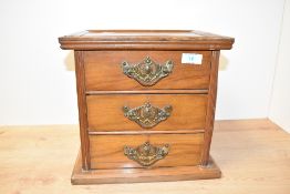 An early 20th century walnut table top chest of three drawers, having a moulded top, plinth base and