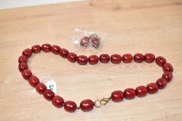 A red resin beaded necklace, having beads of oval form with matching earrings